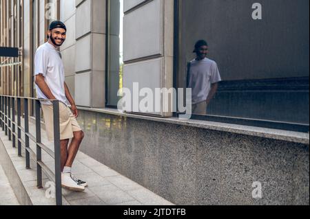 Un bell'uomo sorridente con uno zaino in strada Foto Stock