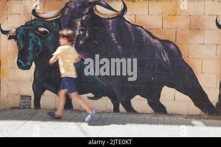 Losar, Spagna - 23th agosto 2022: Bambino che corre accanto a pareti decorate con graffiti a Losar de la vera, Caceres, Estremadura, Spagna Foto Stock