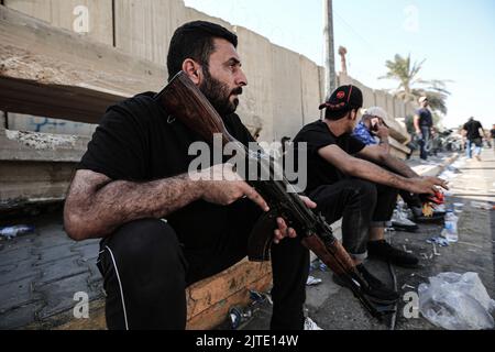 Baghdad, Iraq. 30th ago, 2022. Membro armato di Saraya al-Salam, l'ala militare collegata al clerico sciita iracheno Muqtada al-Sadr è raffigurata durante gli scontri con le forze di sicurezza irachene nella zona verde dell'Iraq. Fonti di sicurezza e assistenza medica irachene hanno riferito che almeno 25 persone sono state uccise e 450 feriti dopo i disordini scoppiati il giorno precedente. Credit: Ameer al-Mohammedawi/dpa/Alamy Live News Foto Stock