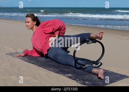 bella donna che si esercita sulla spiaggia con pilates anello Foto Stock