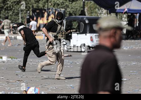 Baghdad, Iraq. 30th ago, 2022. I membri armati di Saraya al-Salam, l'ala militare collegata al clerico sciita iracheno Muqtada al-Sadr, corrono durante gli scontri con le forze di sicurezza irachene nella zona verde dell'Iraq. Fonti di sicurezza e assistenza medica irachene hanno riferito che almeno 25 persone sono state uccise e 450 feriti dopo i disordini scoppiati il giorno precedente. Credit: Ameer al-Mohammedawi/dpa/Alamy Live News Foto Stock