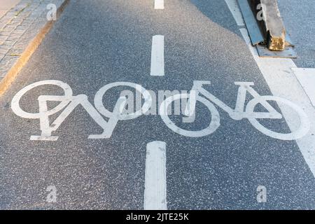 Simboli bianchi della bicicletta sull'asfalto che segnano le corsie della bicicletta Foto Stock