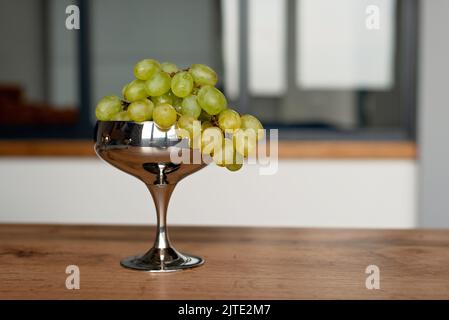 Un mazzo di uve verdi mature in una ciotola di metallo su un tavolo di legno. Cibo, alimentazione sana. Messa a fuoco selettiva morbida. Foto Stock