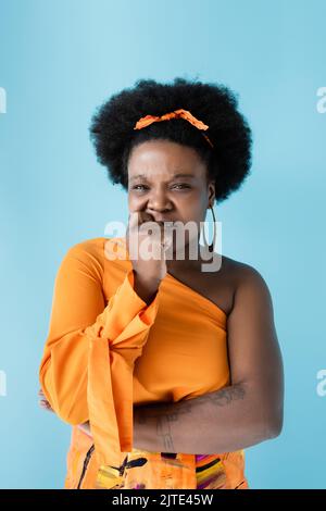 tatuato e preoccupato corpo afro-americano positivo donna isolato su blu, immagine stock Foto Stock