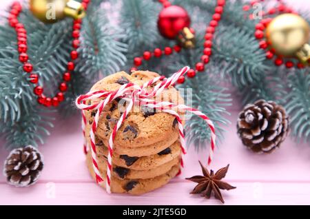 Biscotti al cioccolato e decorazione natalizia su tavolo di legno rosa Foto Stock