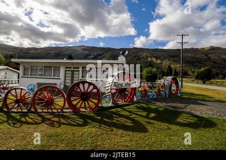 Una casa residenziale / bungalow con il suo recinto giardino di vecchie ruote locomotive a Kingston vicino Queenstown in Otago, una regione sud-orientale di South Isl Foto Stock
