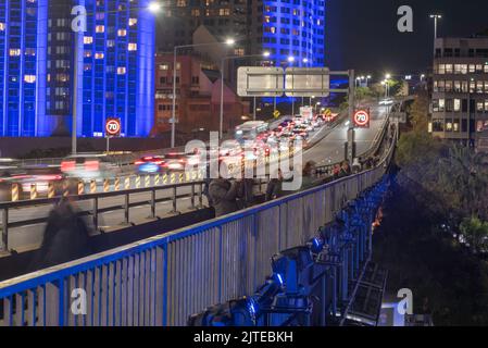 Con edifici illuminati dietro di loro e proiettori di luce montati sotto, fotografi con telecamere, cavalletti e telefoni si allineano lungo la Cahill Expressway Foto Stock