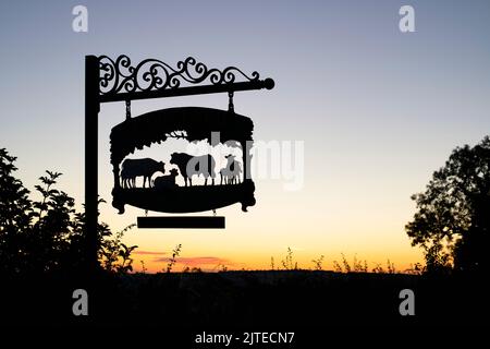 Park Farm segno con Stow on the Wold nella distanza, Cotswolds, Gloucestershire, Inghilterra. Silhouette Foto Stock