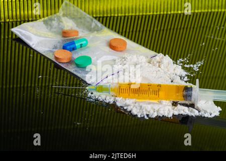 Compresse colorate e pillole con siringa e cocaina in polvere. Molte droghe varie. Foto Stock