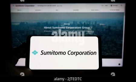 Persona che tiene in mano uno smartphone con il logo della società giapponese Sumitomo Corporation sullo schermo davanti al sito Web. Messa a fuoco sul display del telefono. Foto Stock