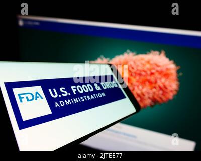 Telefono cellulare con il logo della FDA (Food and Drug Administration) degli Stati Uniti sullo schermo di fronte al sito web. Messa a fuoco a sinistra del display del telefono. Foto Stock