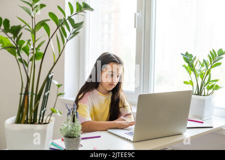 Bambina che impara l'inglese al chiuso a lezione online Foto Stock