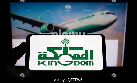 Persona che tiene uno smartphone con il logo della Saudi Arabian Kingdom Holding Company (KHC) sullo schermo di fronte al sito Web. Messa a fuoco sul display del telefono. Foto Stock