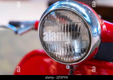 faro, manubrio e leve di comando di uno scooter rosso d'epoca. Foto Stock