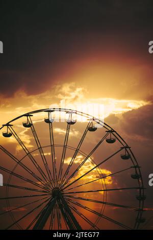 Ruota panoramica nel parco divertimenti e nuvole sceniche al tramonto in cielo e silhouette di uccelli volanti Foto Stock