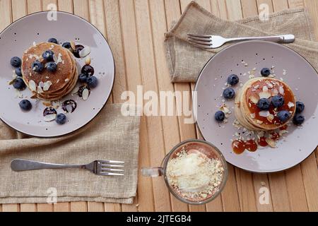 Pancake vegani tradizionali con mirtilli freschi e sciroppo di agave. Cioccolato belga con gelato in vetro. Colazione sana all'aperto. Foto Stock