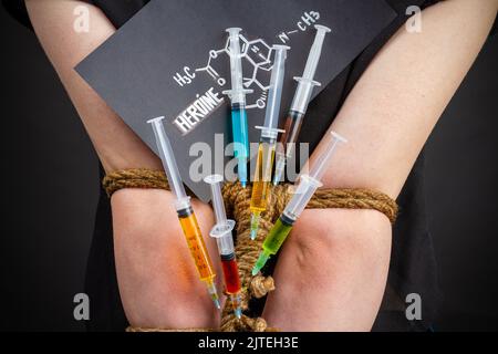 Siringhe colorate per primo piano con stucchi a braccia e molecole di eroina. Concetto di dipendenza da droga e dipendenza. Foto Stock