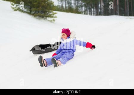 bambini piccoli con slitte sulla collina della neve nel parco d'inverno Foto Stock