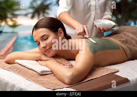 donna e cosmetologa che applicano maschera di argilla in spa Foto Stock