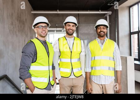 felice sorridente architetti maschi in caschi in ufficio Foto Stock