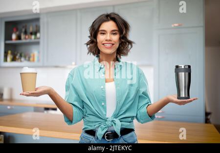 donna che confronta tumbler e tazza di caffè di carta Foto Stock