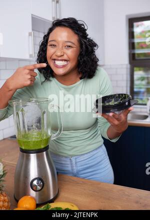 Una giovane donna multietnica assaggia il suo frullato verde appena fatto in cucina Foto Stock