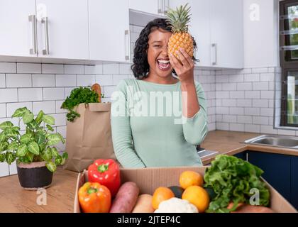 Una giovane donna vegana tiene in mano un ananas con frutta e verdura in scatola consegna Foto Stock