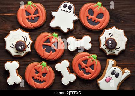 Biscotti di pan di zenzero di Halloween - zucche, fantasmi, ragno e ossa su uno sfondo di legno. Vista dall'alto. Foto Stock