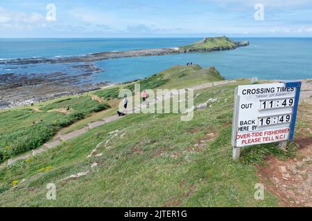 Camminatori diretti verso la testa del Worm, con la strada sopraelevata esposta in caso di marea in discesa, Rhossili, la penisola di Gower, Galles, Regno Unito, Settembre. Foto Stock