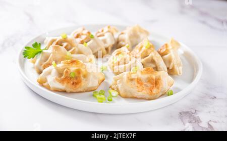 Gnocchi fritti . Gyoza. Alimentazione sana e giovani cipollotti primavera. Cibo asiatico. Tradizionali Gyozas asiatiche su sfondo chiaro. Foto Stock