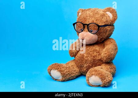 giocattolo marrone orsacchiotto in occhiali su sfondo blu Foto Stock
