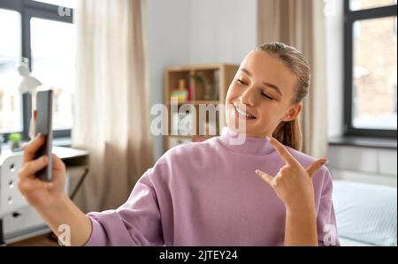 Felice ragazza con lo smartphone tenendo selfie a casa Foto Stock