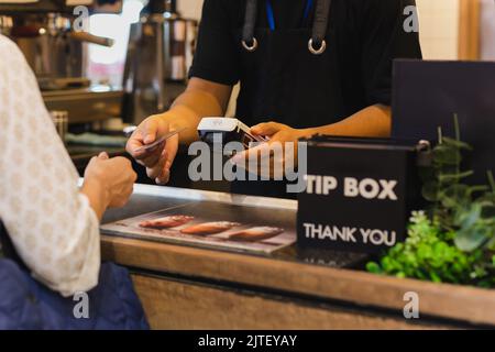 Asia donna utilizzare senza contanti wifi paywave scansione sul lettore di carte in caffetteria. Foto Stock