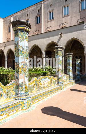 Colonnato con piastrelle colorate che decorano il giardino all'interno del monastero di Napoli, Italia Foto Stock