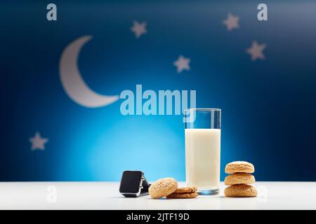bicchiere di latte, biscotti e smart watch di notte Foto Stock
