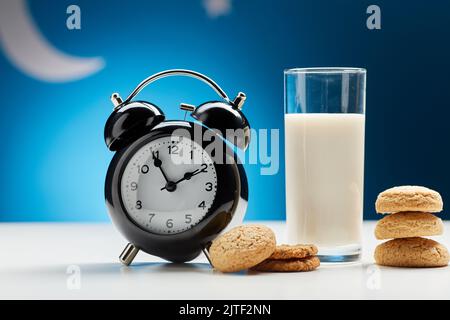 bicchiere di latte, biscotti e sveglia di notte Foto Stock