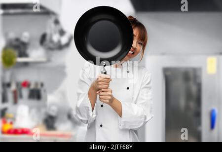 chef che si sbirciava da dietro la padella in cucina Foto Stock