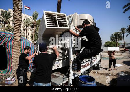 Baghdad, Iraq. 30th ago, 2022. I sostenitori dell'influente clerico sciita iracheno Muqtada al-Sadr, accaparrano i loro effetti personali mentre si ritirano dal loro sito di protesta vicino all'edificio del parlamento all'interno della zona verde di Baghdad. Moqtada al-Sadr ordinò ai suoi seguaci di ritirarsi dal loro sito di protesta a Baghdad martedì, dopo che gli scontri mortali hanno lasciato almeno 25 morti. Credit: Ameer al-Mohammedawi/dpa/Alamy Live News Foto Stock