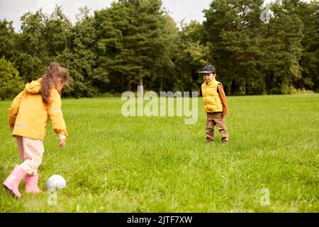 bambini piccoli con la palla che gioca a calcio al parco Foto Stock