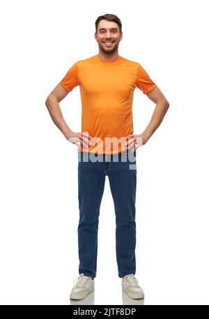 felice uomo sorridente in t-shirt arancione e jeans Foto Stock