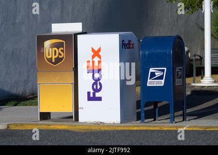 Snohomish, WA, USA - 29 agosto 2022; fila di scatole di raccolta per UPS, FedEx e United States Postal Service con marchio e logo in corrispondenza del marciapiede Foto Stock