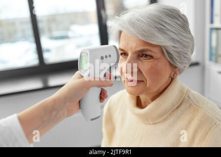 medico con termometro e donna in ospedale Foto Stock