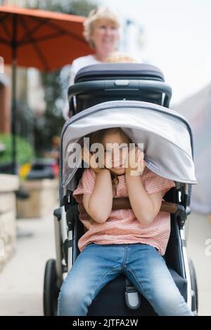 Nonna con nipote sulking (2-3) in passeggino Foto Stock