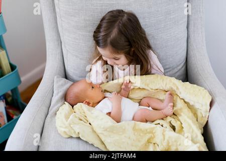 Ragazza (2-3) che tiene neonato fratello (0-1 mesi) Foto Stock