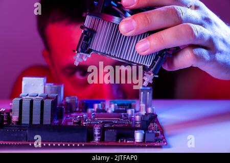 La mano di un uomo inserisce un refrigerante nel socket della scheda madre, primo piano Foto Stock