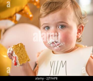 Baby girl (12-17 mesi) mangiare la torta di compleanno Foto Stock