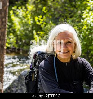 Stati Uniti, Idaho, Stanley, donna bionda anziana che riposa dal flusso di corsa vicino a Sun Valley Foto Stock