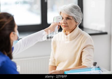 medico con termometro e donna in ospedale Foto Stock