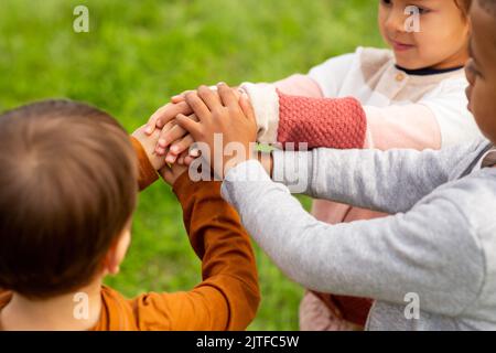 gruppo di bambini che accatastano le mani al parco Foto Stock