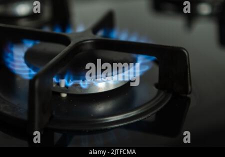 Vista ravvicinata della fiamma blu del gas naturale che brucia nei bruciatori di una cucina moderna Foto Stock